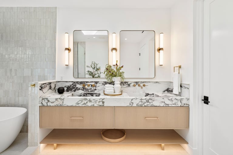 Modern bathroom with marble countertop, dual mirrors, and elegant lighting, featuring a stylish vanity.
