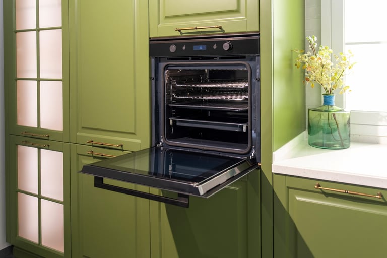 Built-in black oven with an open door, integrated into green cabinetry