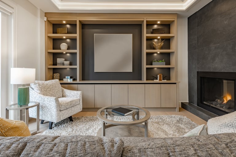 spacious living room in a newly constructed home staged professionally with fireplace view to kitchen grey sofa area rug built in cabinets and shelving recessed lighting