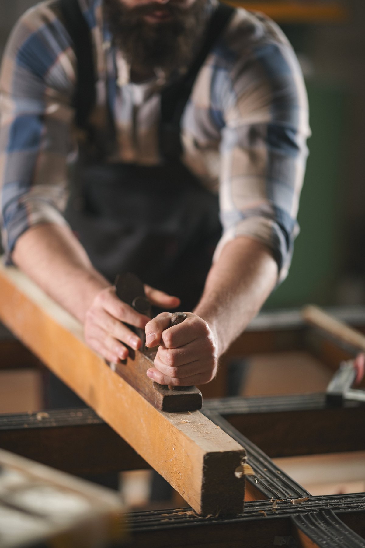 Young carpenter working with wood. Shallow DOF. Developed from RAW; retouched with special care and attention; Small amount of grain added for best final impression.16 bit Adobe RGB color profile.